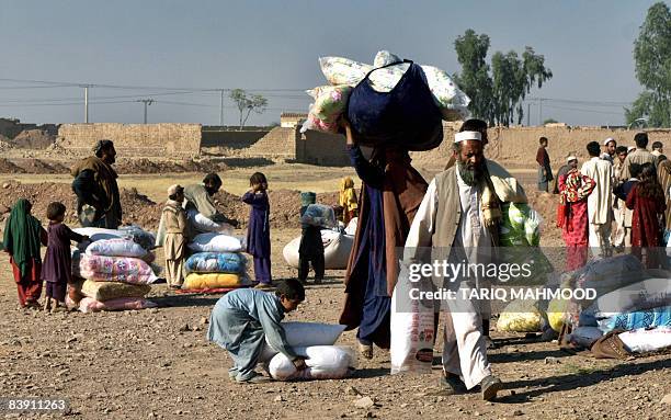 Pakistani people from the Tribal areas made homeless by the ongoing conflict walk away after receiving relief goods at the Jalozai camp some 40kms...