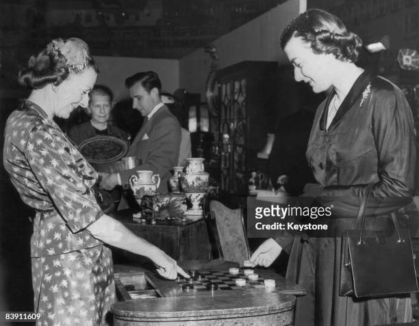 Countess Mountbatten of Burma opens the Antique Dealers' Fair at Grosvenor House, London, 8th June 1955. Here she plays chequers with her daughter...