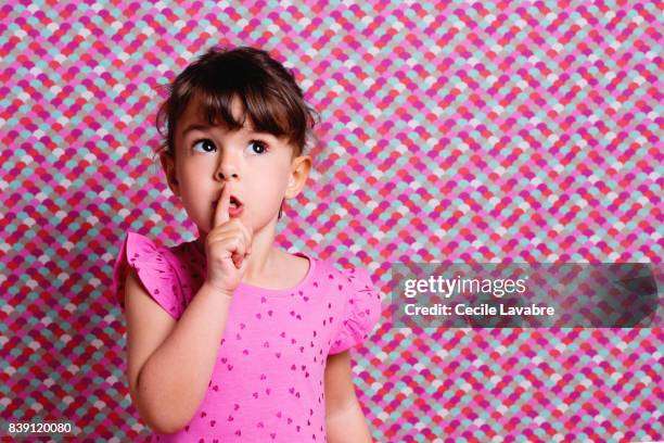girl with finger by mouth, portrait - shhh stock-fotos und bilder