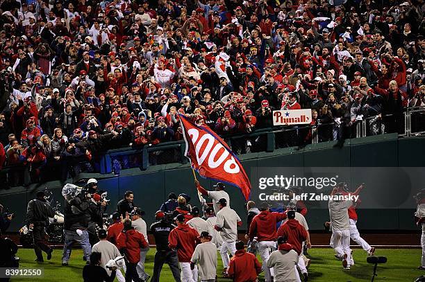 Ryan Howard of the Philadelphia Phillies runs with a "2008" championship flag as fans celebrate after the Phillies won 4-3 against the Tampa Bay Rays...