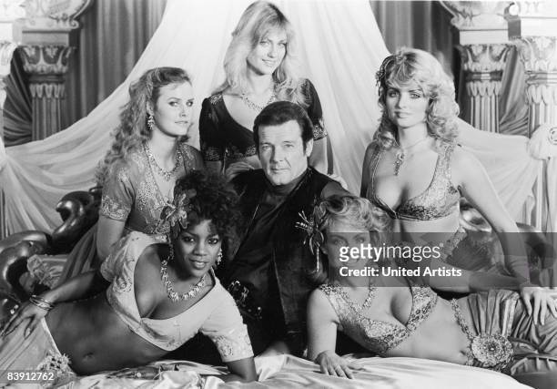 Promotional shot of British actor Roger Moore surrounded by female palace guards in the film 'Octopussy', 1983. Clockwise from top, they are Carolyn...
