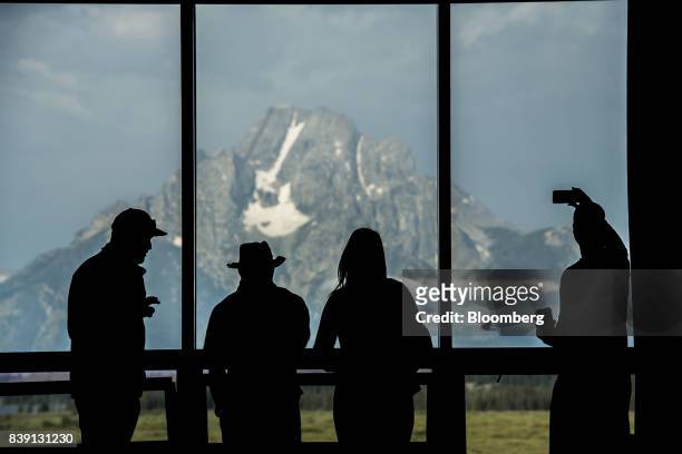 The silhouettes of tourists are seen viewing the Grand Teton mountain range outside of the Jackson Lake Lodge during the Jackson Hole economic...