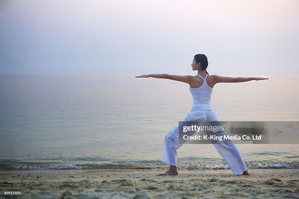 Womand doing yoga on beach.