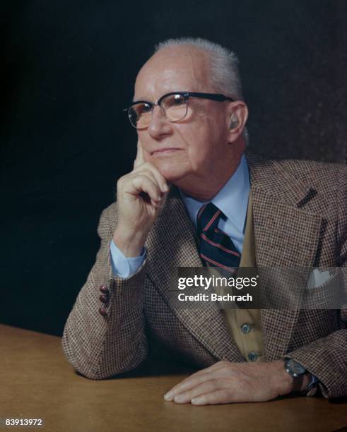 Portrait of American architect, inventor and futurist Buckminster Fuller as he sits at a table with his hand on his chin, Boston, Massachussetts,...