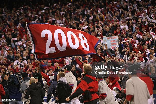 Ryan Howard of the Philadelphia Phillies runs with a "2008" championship flag as fans celebrate after the Phillies won 4-3 against the Tampa Bay Rays...