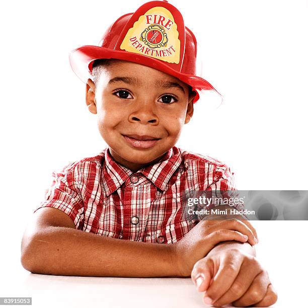 young boy wearing fireman hat - feuerwehrhelm stock-fotos und bilder