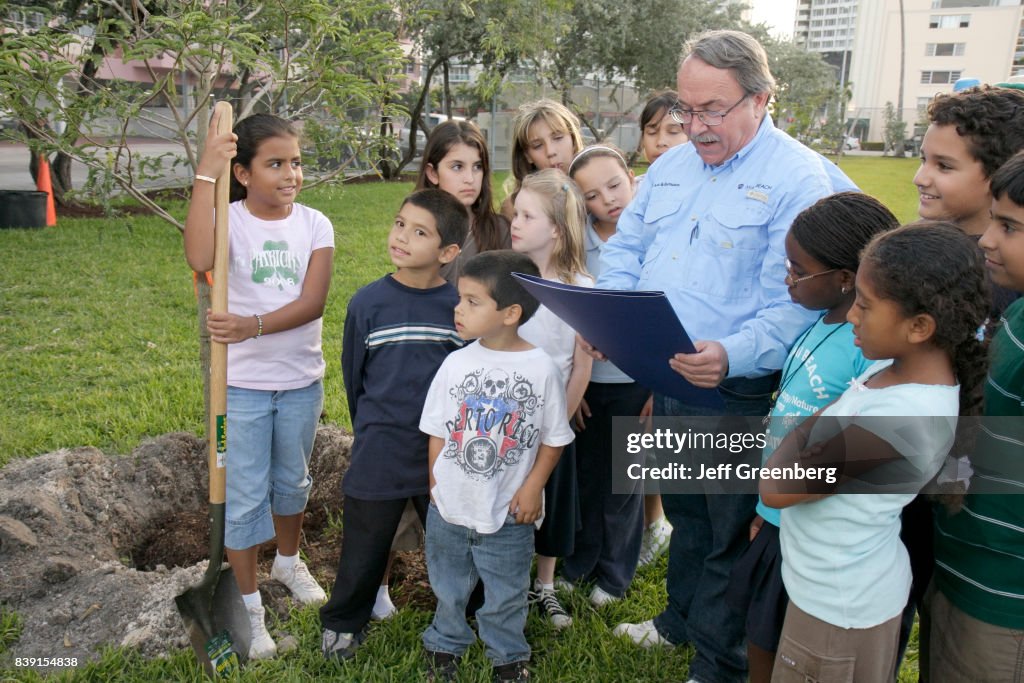 A man reading a proclamation to a group of children at the Earth Arbor Day family event for Captain Planet's Carnival.