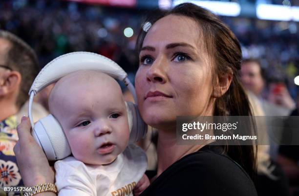 Dee Devlin holds Conor McGregor Jr. And watches as Conor McGregor pose on the scale during his official weigh-in at T-Mobile Arena on August 25, 2017...