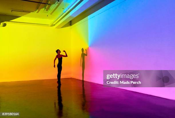 woman standing in a large studio space - yellow perch - fotografias e filmes do acervo