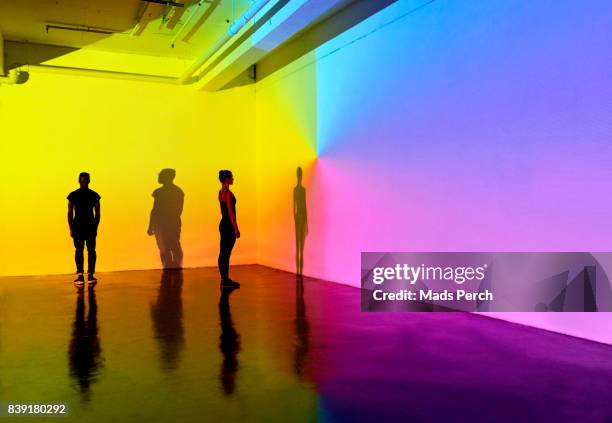 man and woman standing in a gallery space with colourful walls - yellow perch stock-fotos und bilder