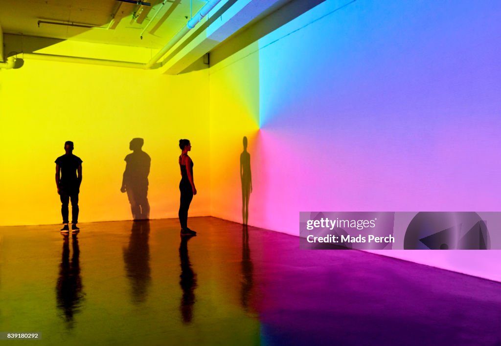 Man and woman standing in a gallery space with colourful walls