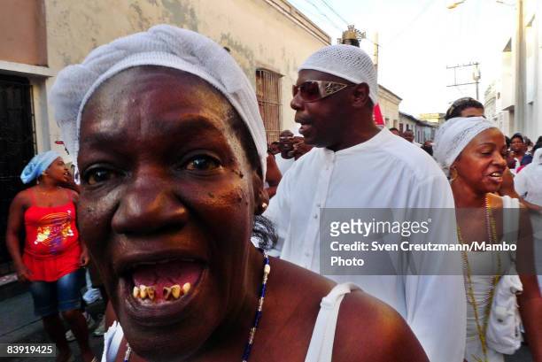 Cuban woman sings as she walks in a procession of people as they carry a statue of Saint Barbara in celebration of the anniversary of the Catholic...