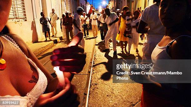 Cubans dance and hold candles after walking in a procession of people where a statue of Saint Barbara was carried in celebration of the anniversary...