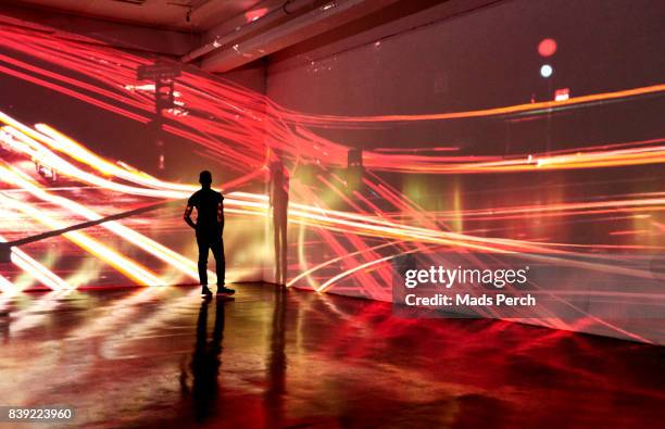man looking at abstract nighttime cityscape being projected in gallery space - art gallery people fotografías e imágenes de stock