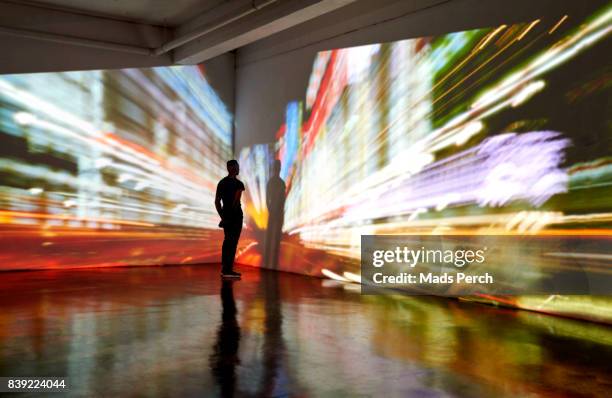 man looking into a nighttime cityscape being projected in gallery space - long exposure people stock pictures, royalty-free photos & images