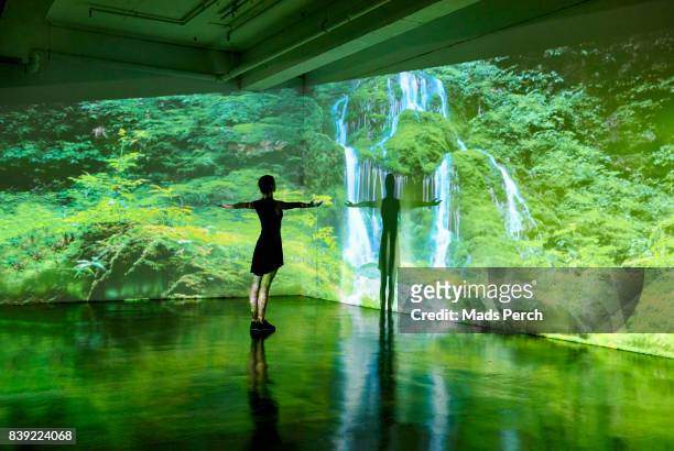 girl looking at a large scale nature image projected on to a wall - ambiente evento fotografías e imágenes de stock