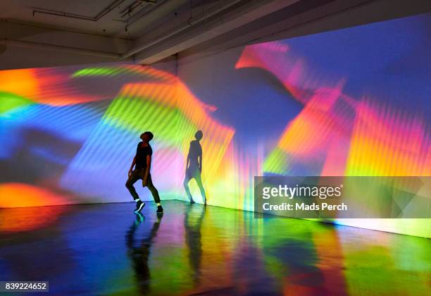man dancing in front of large scale colourful projected image - arts culture and entertainment stock-fotos und bilder