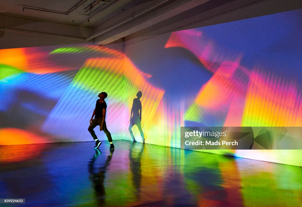 Man dancing in front of large scale colourful projected image