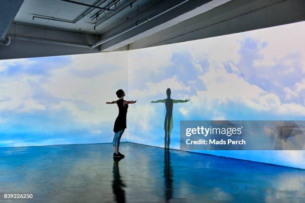 girl looking into a large scale projected image of skies - projection mapping stock-fotos und bilder