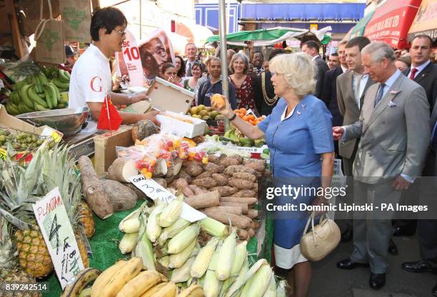 The Duchess of Cornwall buys a mango as The Prince of Wales looks, during a visit to Brixton Market, in Brixton, south London. Prince Charles and the...