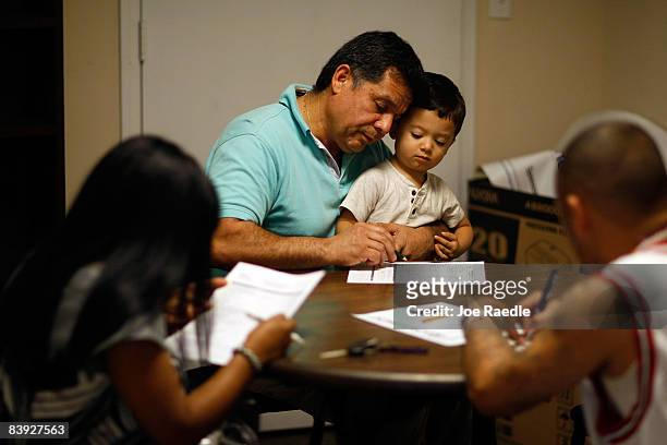 Juan Carlos Rojas holds his 2 year old son, Juan Pablo Rojas, after being laid off from his job this morning, as he fill out paperwork for...