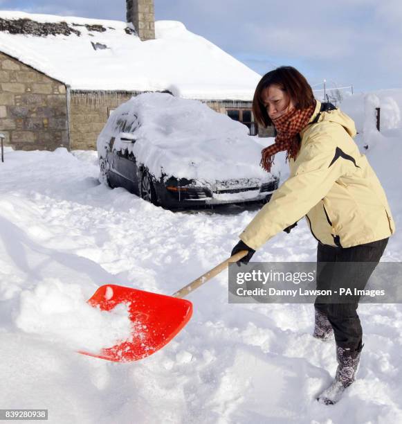 Anne Wilson clears snow from her driveway in Corvichen, Scotland, as snow and ice continued to cause havoc across Britain.