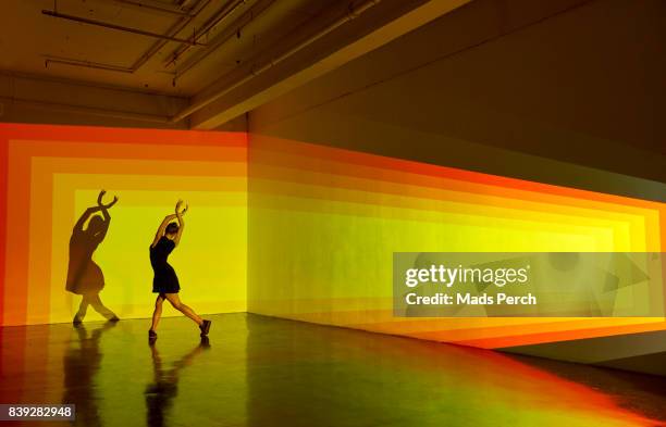 girl dancing in a large space with graphic patterns projected around her - projection mapping stock-fotos und bilder