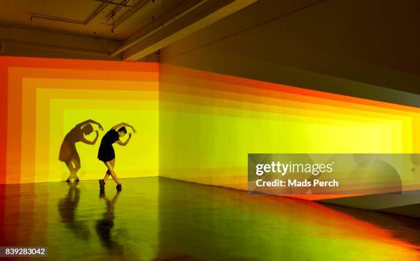 girl dancing in a large space with graphic patterns projected around her - yellow perch stock-fotos und bilder