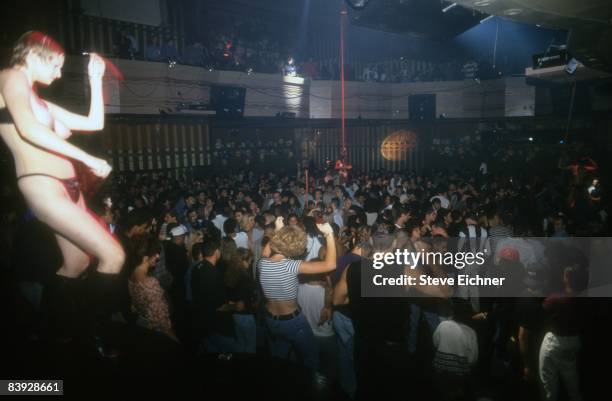 Topless woman dances on stage while other patrons dance during a party held inside New York City's Webster Hall, 1993.