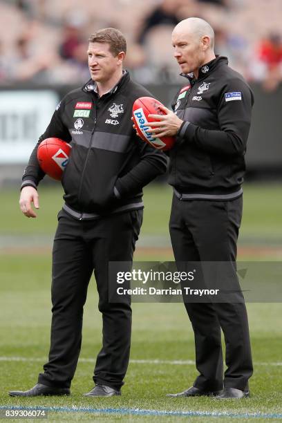 Collingwood assistant coachs Scott Burns and Brenton Sanderson look on before the round 23 AFL match between the Collingwood Magpies and the...