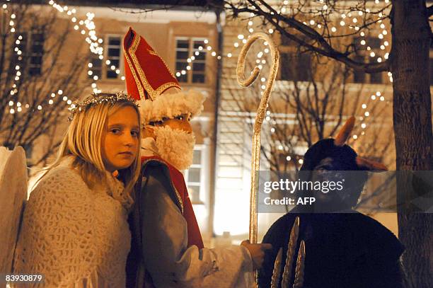 Children dressed as an angel, St. Nicholas, in Czech tradition known as Svaty Mikulas and the devil walk on 05 November 2008 on their way to meet...