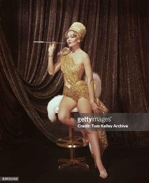 Woman dressed as a flapper flaunts the cigarette she's smoking in a cigarette holder, ca.1960s. United States.