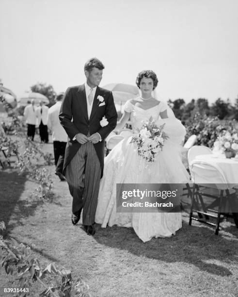 Scene from the Kennedy-Bouvier wedding. Groom John walks alongside his bride Jacqueline at an outdoor reception, 1953. Newport, Rhode Island.