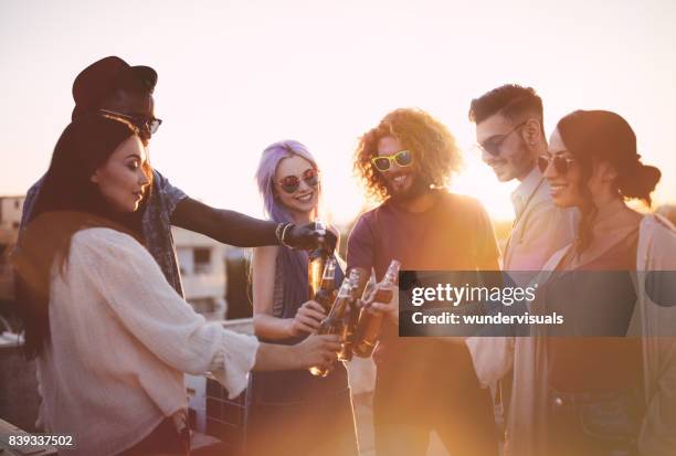 felizes multi-étnica amigos brindando com bebidas no verão terraço festa - beer bottle - fotografias e filmes do acervo