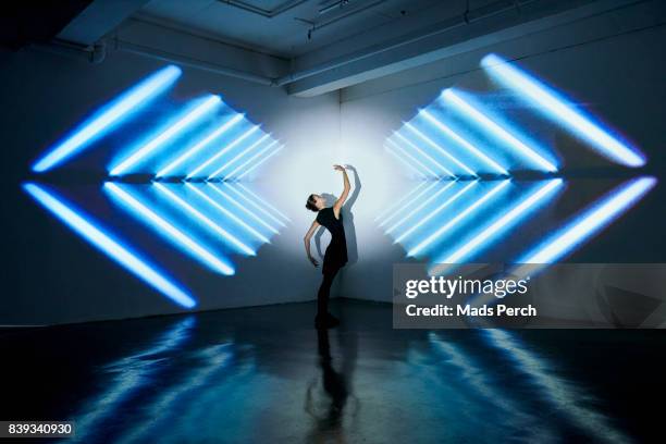 girl dancing in a studio with graphic patterns projected onto wall behind her - symmetry people stock pictures, royalty-free photos & images