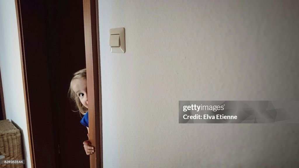 Child peaking around a door frame