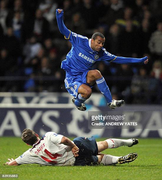 Chelsea's English defender Ashley Cole hurdles a tackle from Bolton Wanderers' English forward Kevin Davies during the English Premier league...