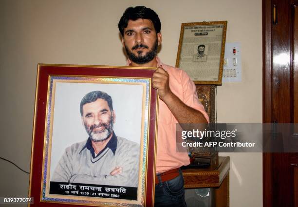 This photo taken on August 25, 2017 shows Indian journalist Anshul Chhatrapati with a portrait of his father Ram Chander Chhatrapati, who...