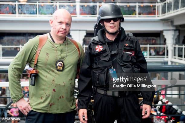 An Umbrella Corporation Guard cosplayer from the Resident Evil Franchise and a John McClane cosplayer seen during Day 1 of the London Super Comic Con...
