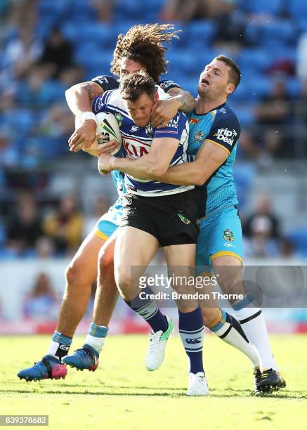 Brett Morris of the Bulldogs is tackled by Kevin Proctor and Anthony Don of the Titans during the round 25 NRL match between the Gold Coast Titans...