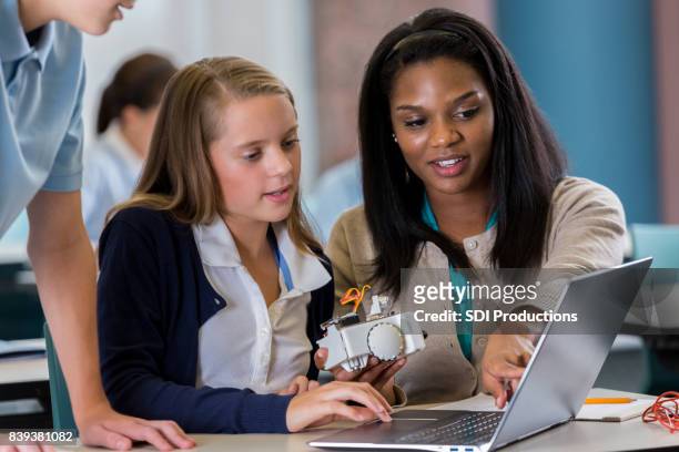 student arbeitet auf laptop mit lehrer im robotiklabor - black girl with computer stock-fotos und bilder