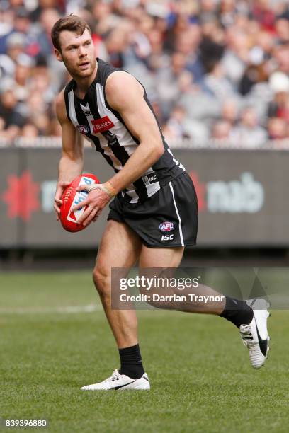 Matt Scharenberg of the Magpies runs with the ball during the round 23 AFL match between the Collingwood Magpies and the Melbourne Demons at...
