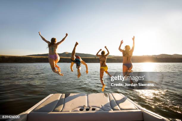 a group of freinds enjoying a day at the lake - jumping of boat stockfoto's en -beelden