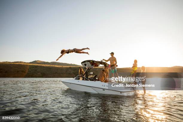 a group of freinds enjoying a day at the lake - jumping of boat foto e immagini stock