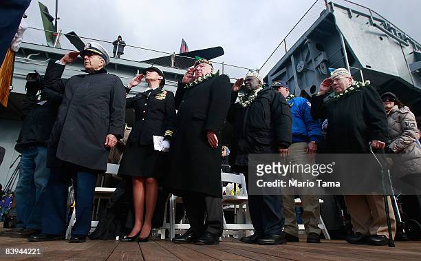 Members of the U.S. Military salute while commemorating the 67th anniversary of the attack on Pearl Harbor at the Intrepid Sea, Air & Space Museum...