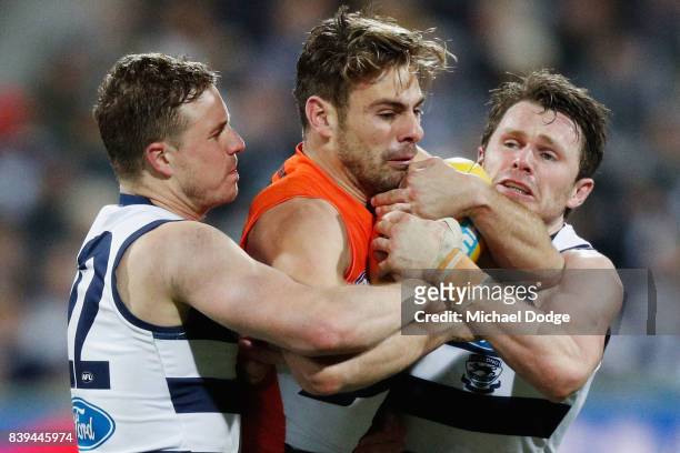 Mitch Duncan and Patrick Dangerfield of the Cats tackle Stephen Coniglio of the Giants during the round 23 AFL match between the Geelong Cats and the...