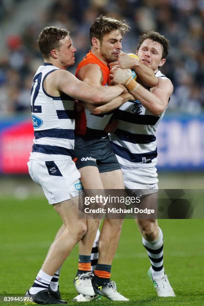 Mitch Duncan and Patrick Dangerfield of the Cats tackle Stephen Coniglio of the Giants during the round 23 AFL match between the Geelong Cats and the...