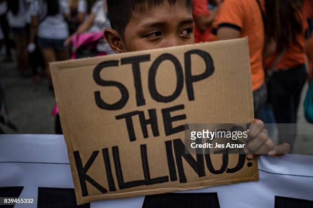 Boy holding a slogan calling to stop extra judicial killings on August 26, 2017 in Caloocan city, Philippines. More than a thousand Filipinos marched...