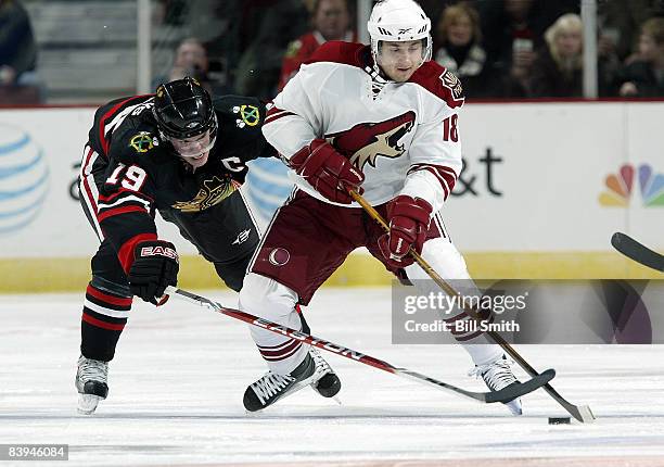 Jonathan Toews of the Chicago Blackhawks reaches around Enver Lisin of the Phoenix Coyotes to get the puck on December 7, 2008 at the United Center...