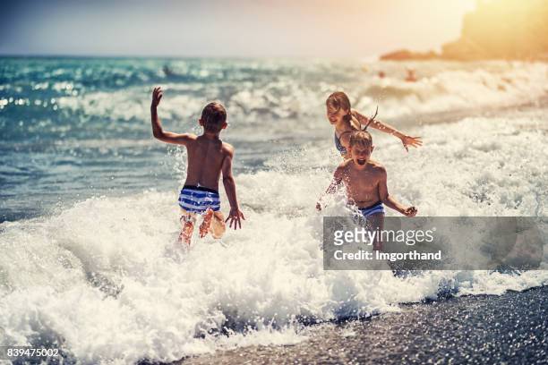 children enjoying huge waves on beach - malaga beach stock pictures, royalty-free photos & images